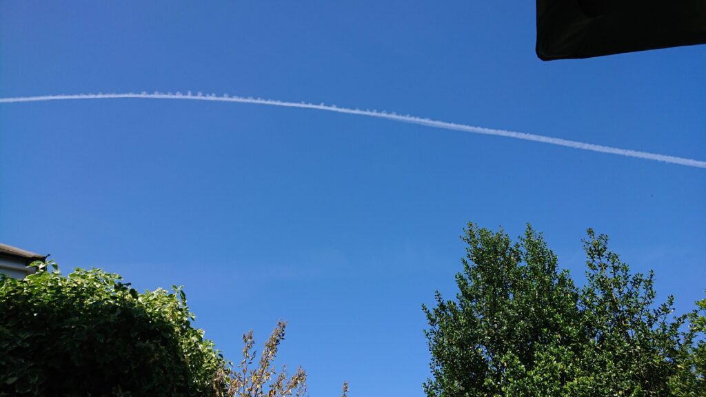 White plane trail in a clear blue sky